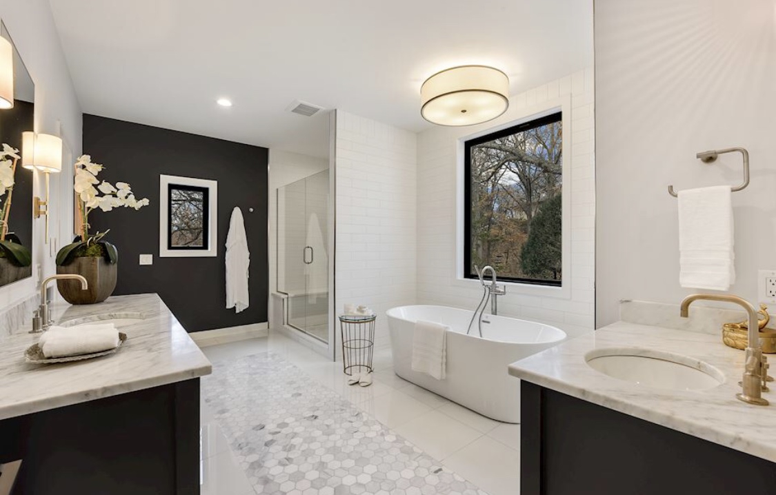 A remodeled bathroom with a freestanding soaking tub and a dark accent wall