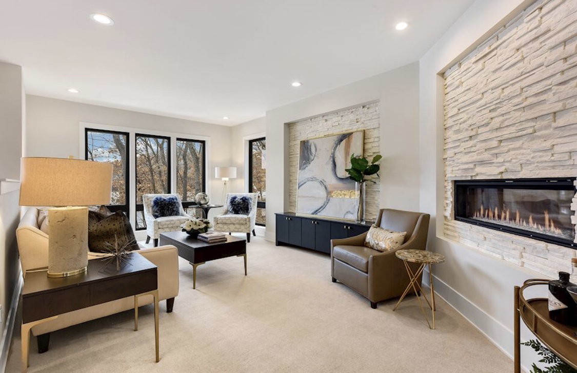 A staged living room with a linear fireplace set in a stacked-stone wall