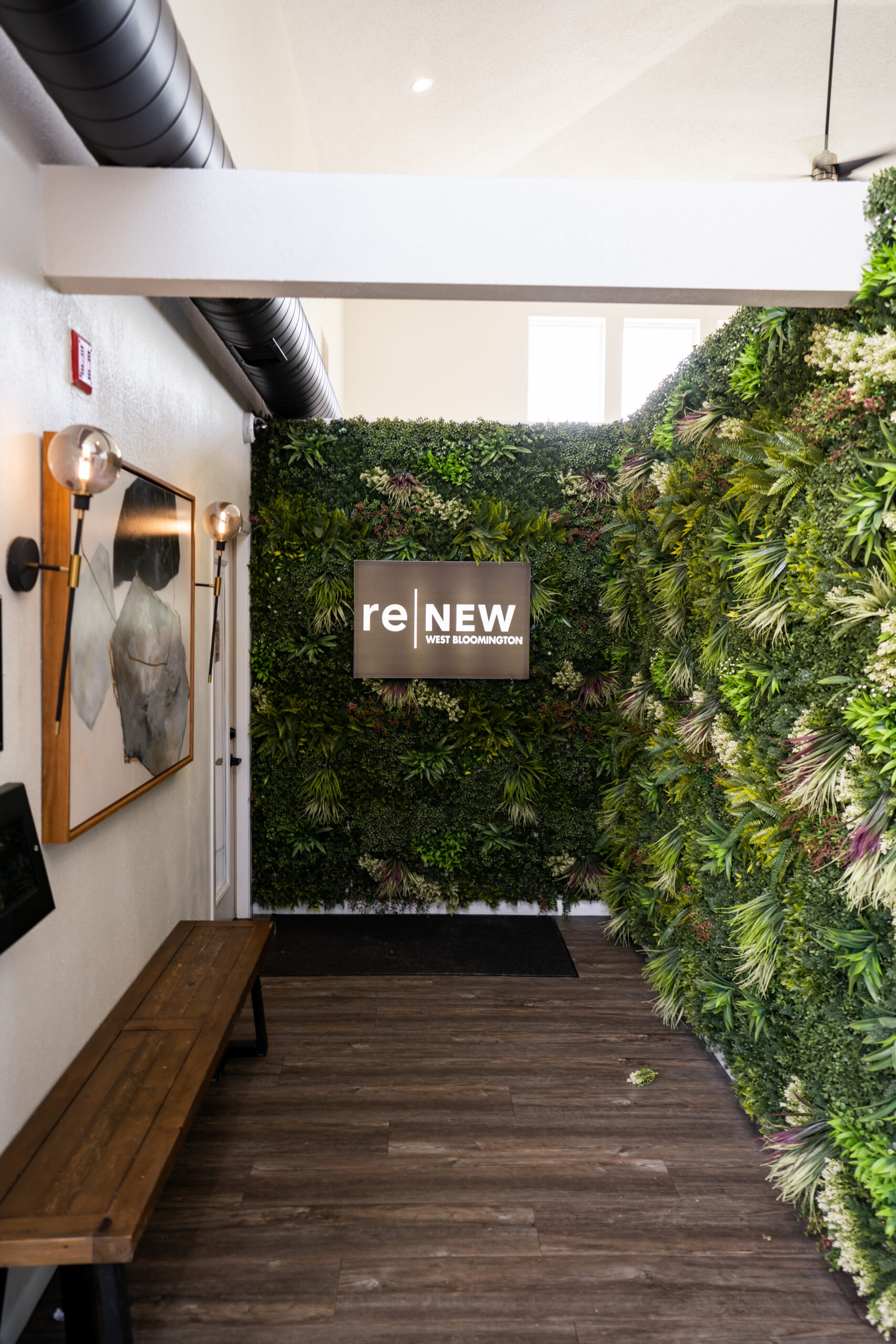 The reception area of Capital City's office with a living greenery wall reading reNEW